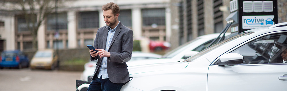 Business man charging EV at office car park