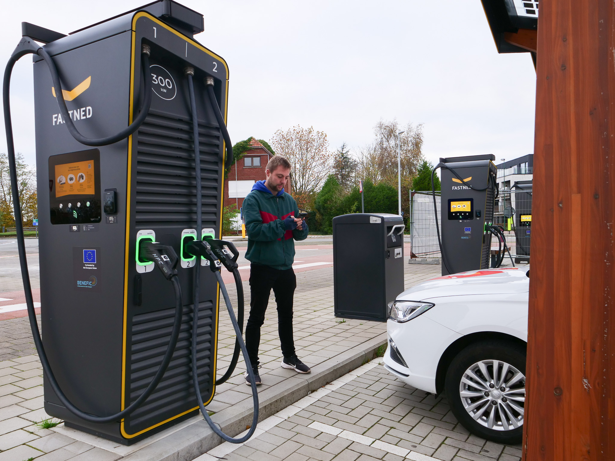 Olly stands next to a Fastned charge point while the Zapmobile charges