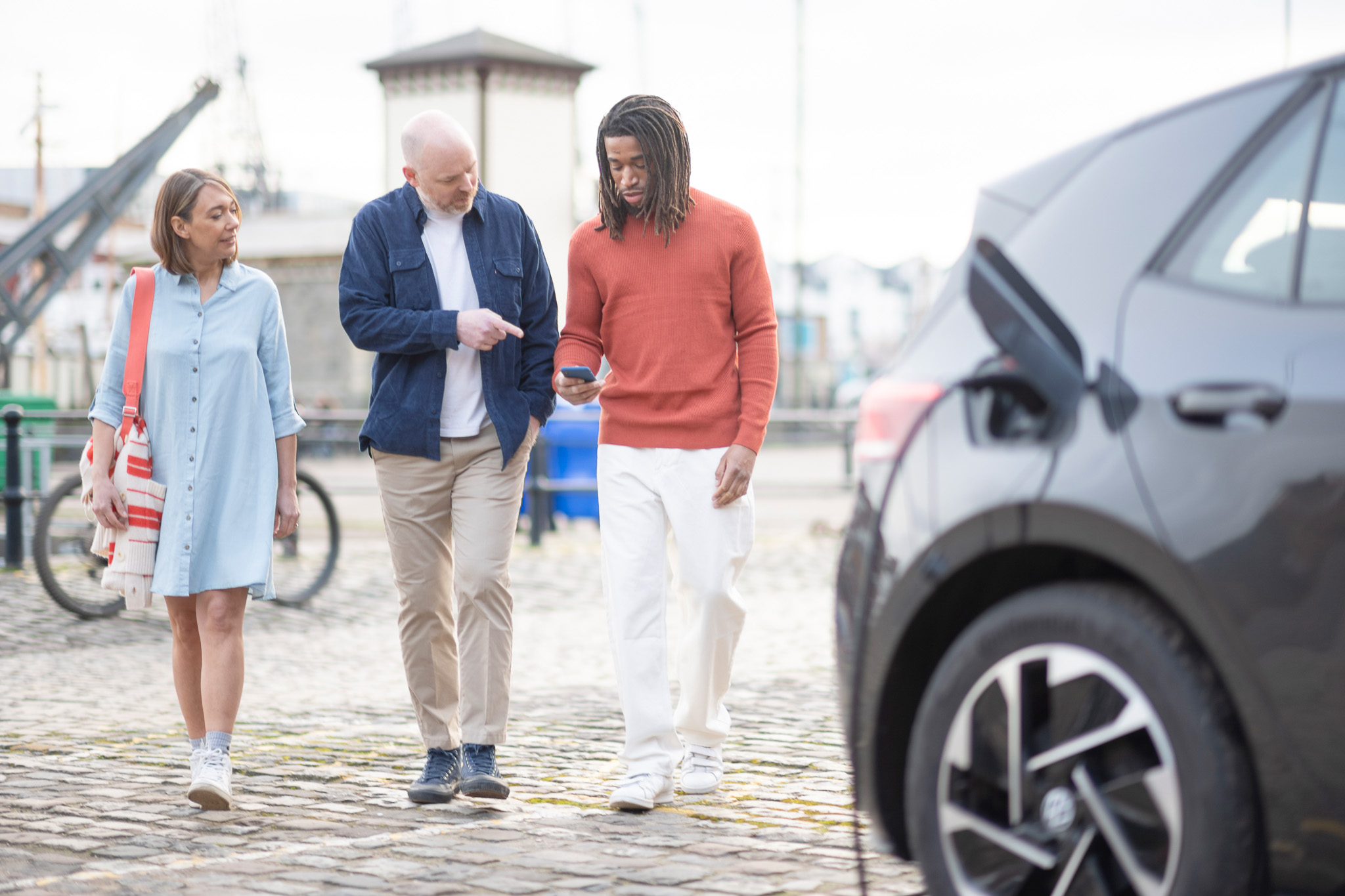 A group of people charge their EV while checking the Zapmap app