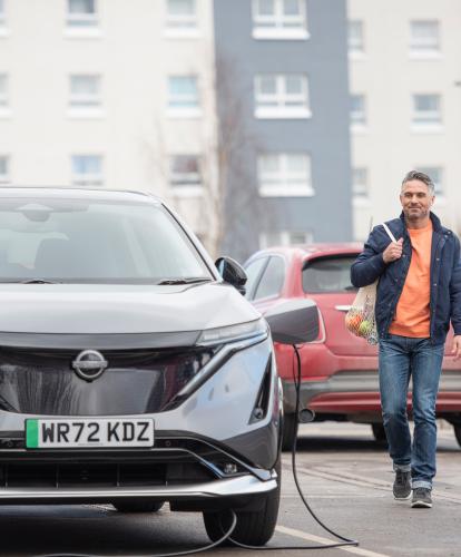 Stock photo - EV charging with man returning to car