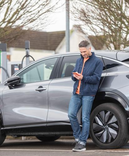 Man charges EV on supermarket car park while using Zapmap on his phone