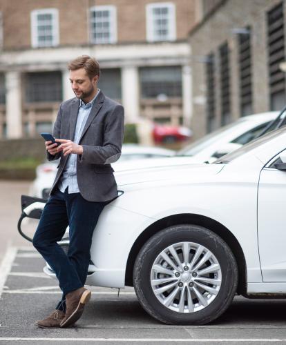Business man checks his phone while his EV is charging
