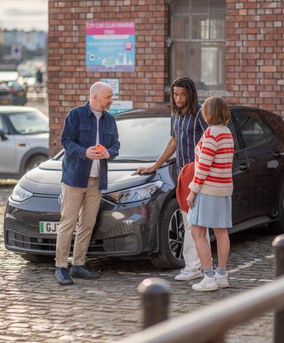 Group of friends chat while their EV is charging in car park