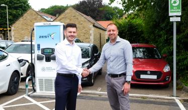 Councillor Duncan and Zest CEO shake hands in front of Zest charge point in car park