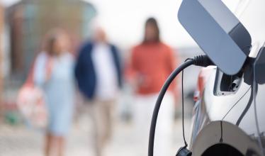 EV charging port, people out of focus in background