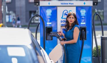 Woman in blue dress charging electric vehicle