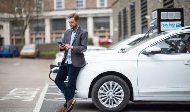 Business man checks his phone while his EV is charging